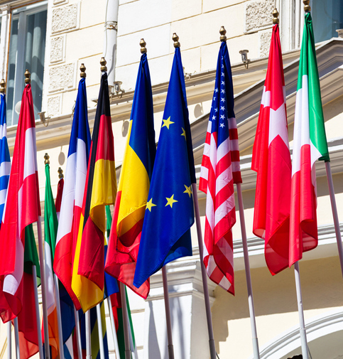 Many flags of the world on the facade of a historic building.